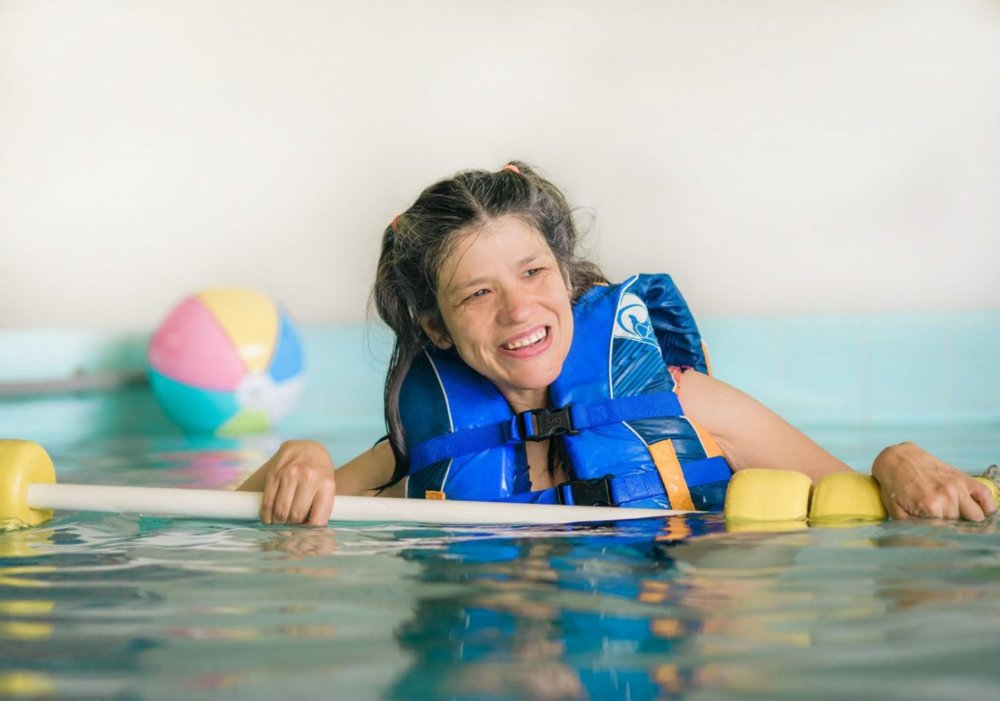 Young woman with disabilities floating in the pool