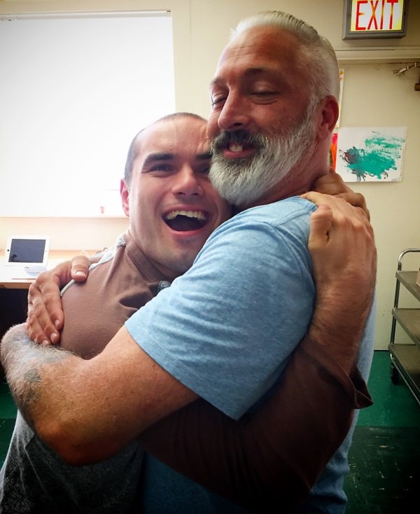 Man hugging male resident of Hillside who is laughing
